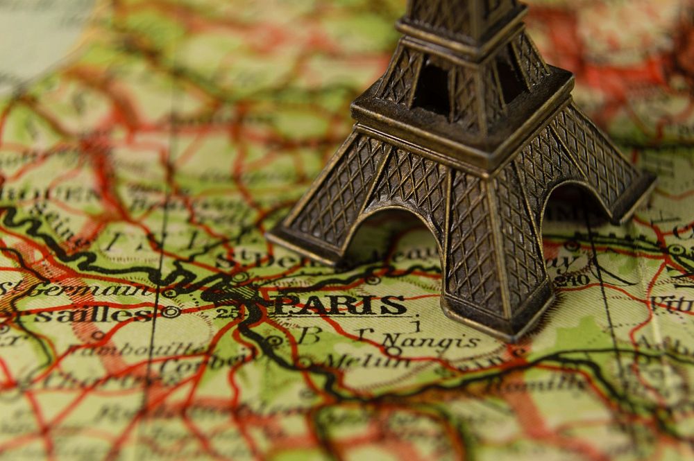 Eiffel tower miniature on a world map. Original public domain image from Wikimedia Commons