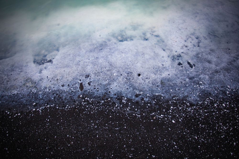 Ocean foam washing on the black sand beach in Iceland. Original public domain image from Wikimedia Commons