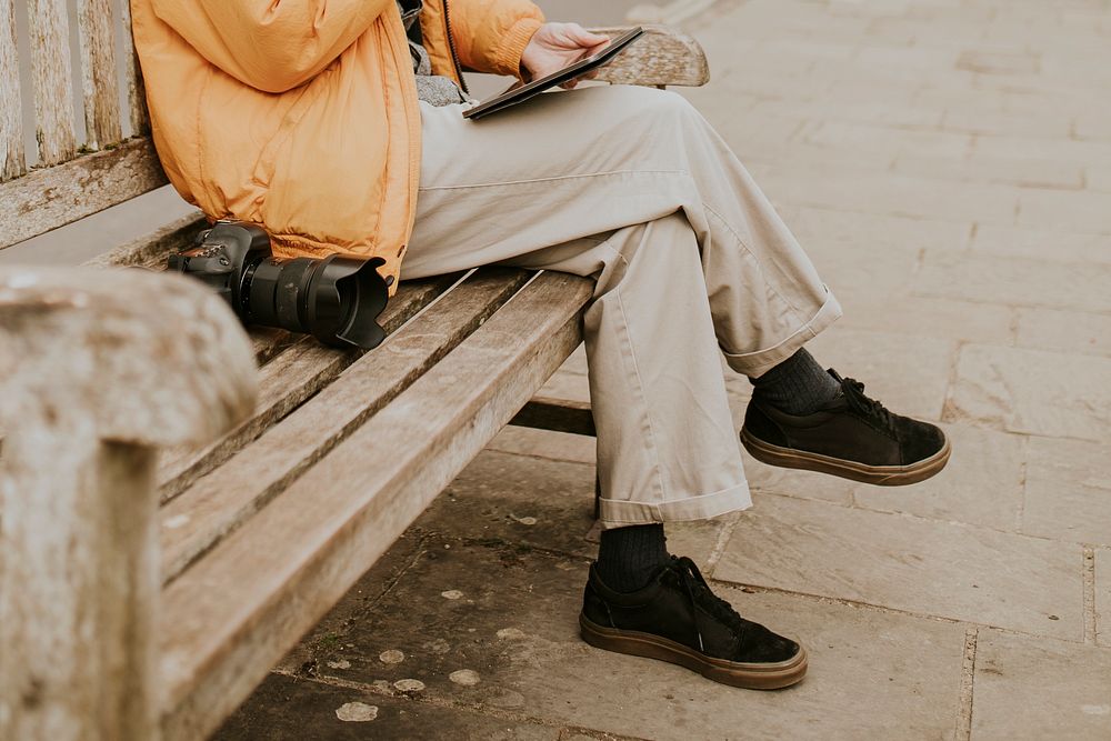 Man sitting on a bench and working on tablet in the village