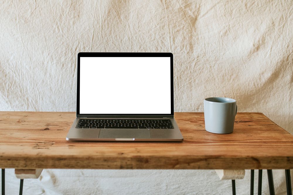 Laptop psd mockup with coffee mug on wooden table