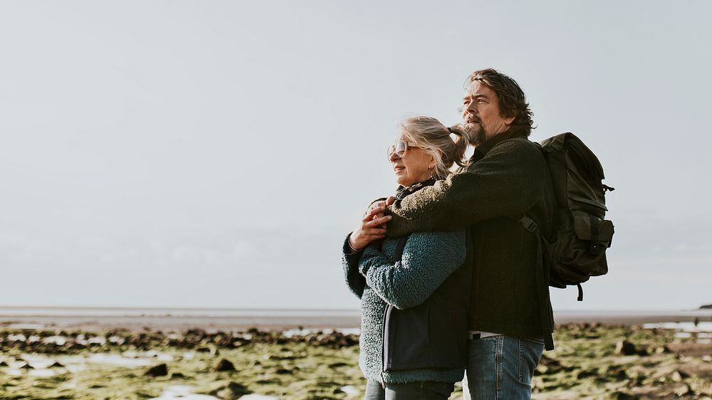 Senior tourist couple hugging at the beach