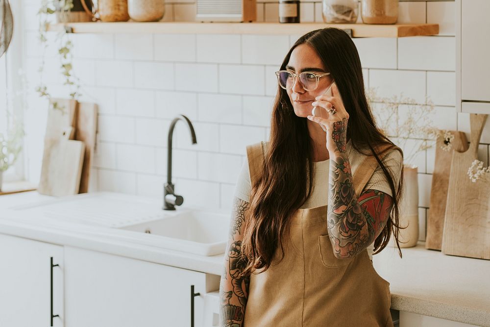 Tattooed woman in the kitchen talking on the phone