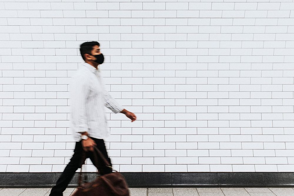 Man walking past a white brick wall