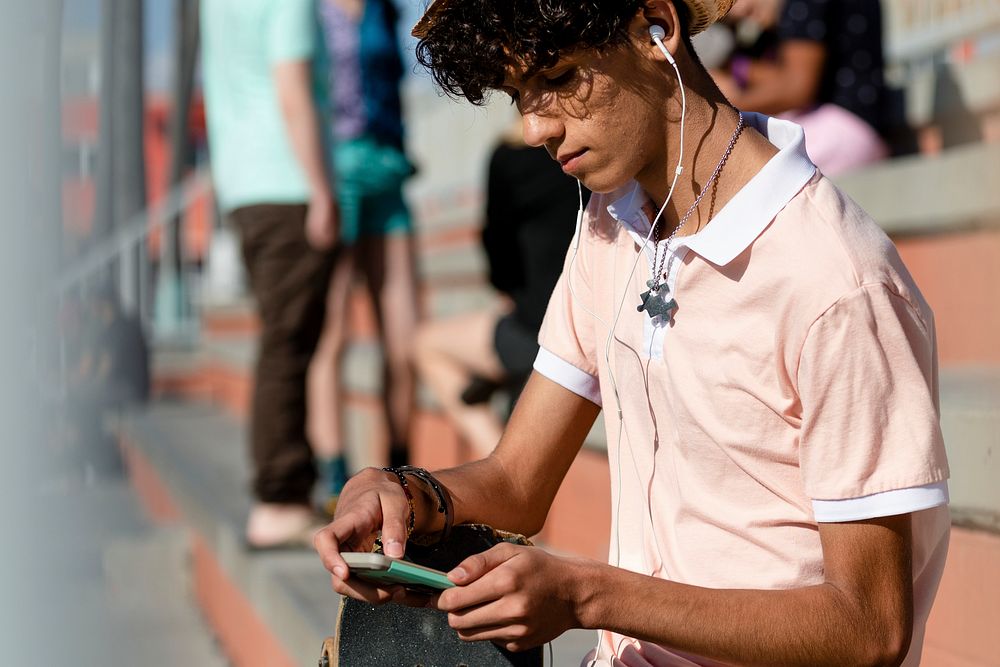 Young adult listen to music, at a skatepark in summer