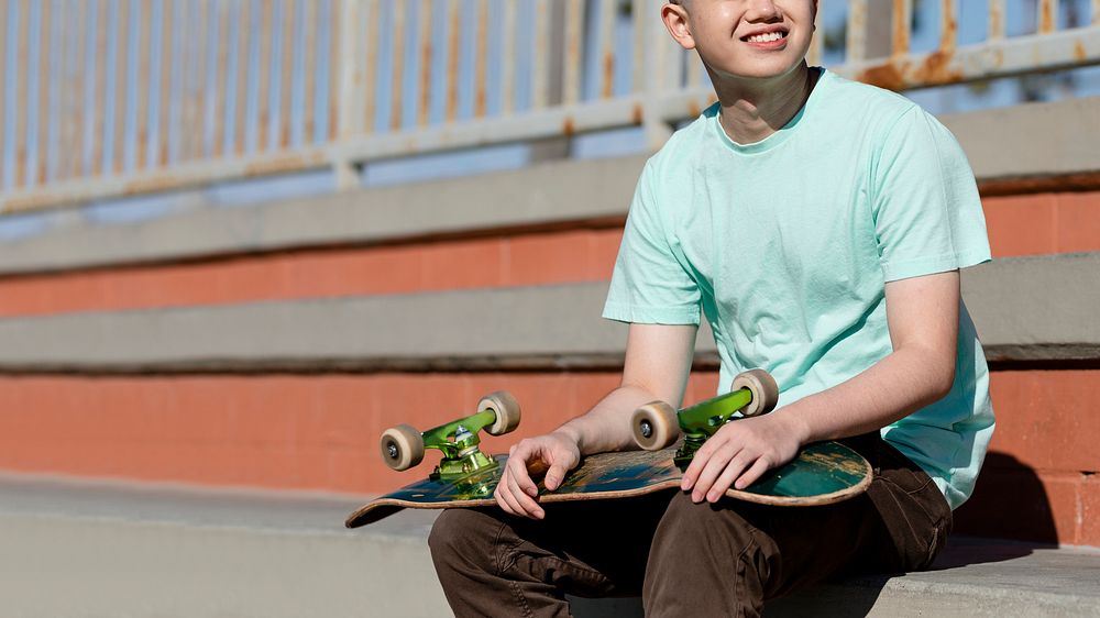 Young adult skater holding a skateboard in Venice Beach, Los Angeles