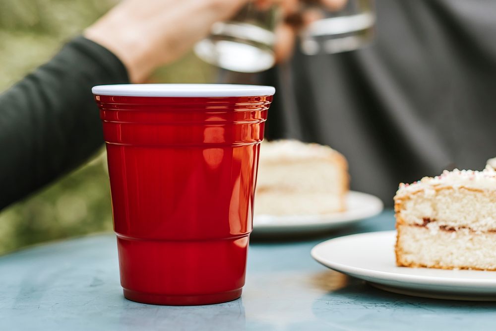Red plastic cup by on a tabele by a cake 