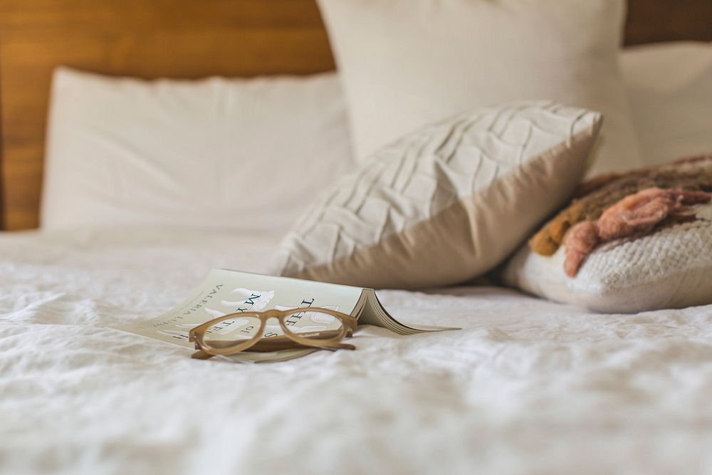 Glasses and a book are waiting and ready for a day of relaxing in bed, , free public domain CC0 photo.