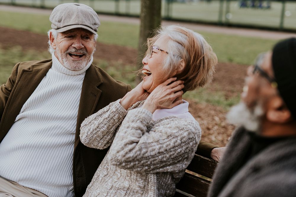 Old friends laughing together on park bench 