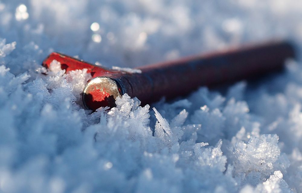 A tent stake lays on the ground partially covered by ice crystals as Soldiers assigned to the 98th Support Maintenance…