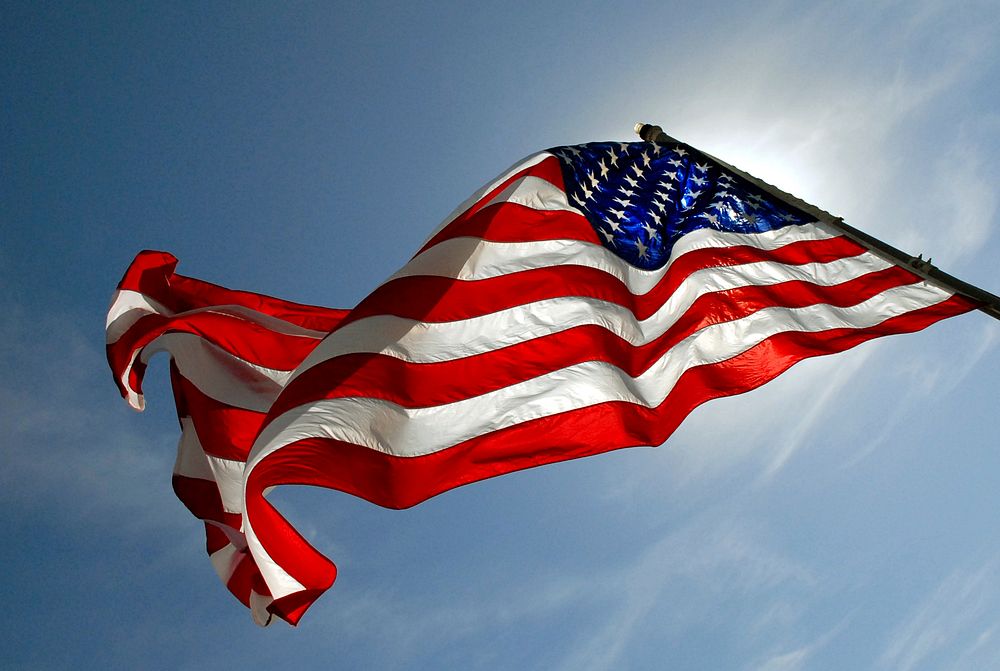 The United States flag against blue sky. Original public domain image from Flickr