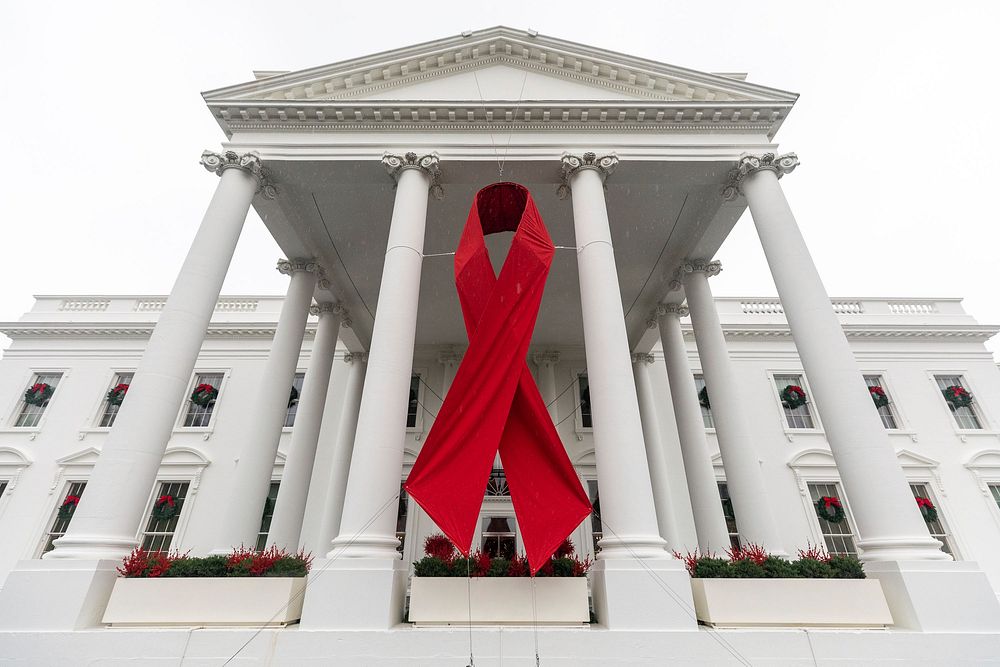 Red ribbon hangs from the North Portico of the White House for World AIDS Day. Original public domain image from Flickr