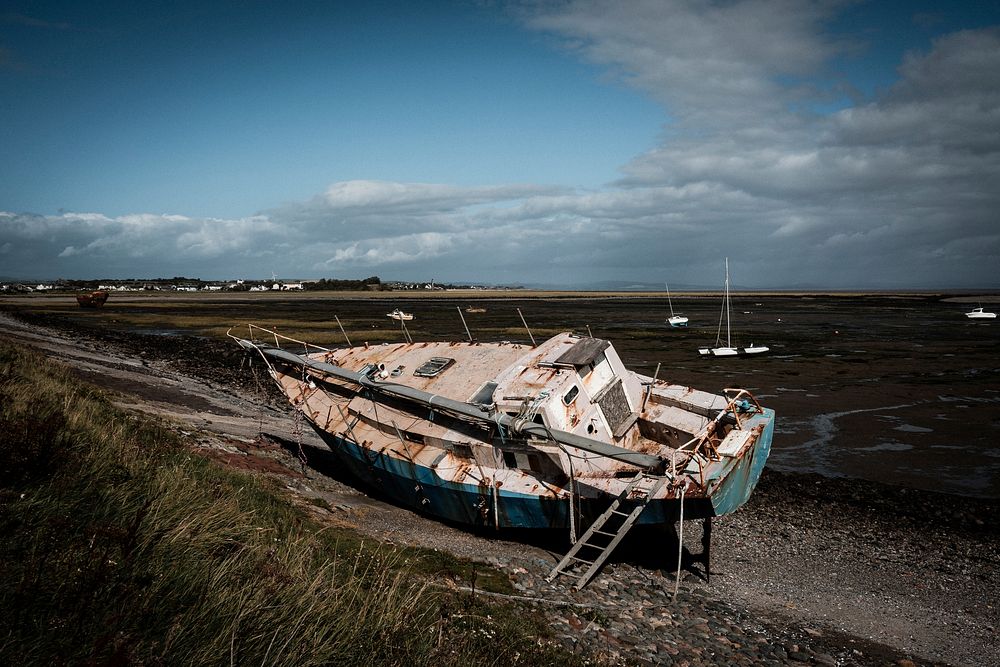 Abandoned rusting sailboat on shore. Original public domain image from Flickr