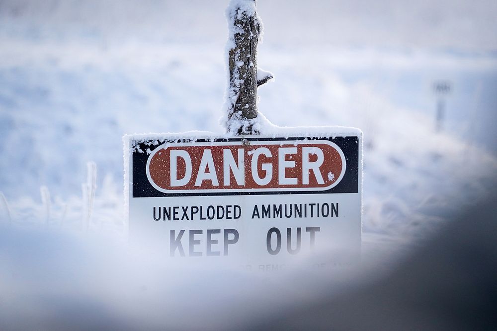 A sign warning of unexploded ammunition is seen covered in hoar frost as paratroopers assigned to the 2nd Battalion, 377th…