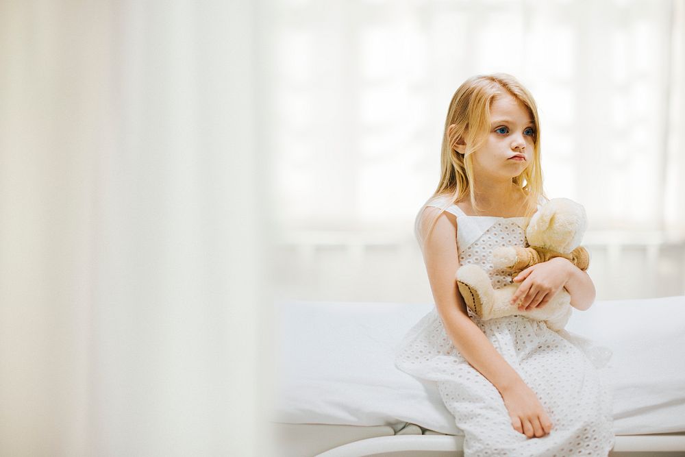 Little girl in hospital, teddy bear background psd