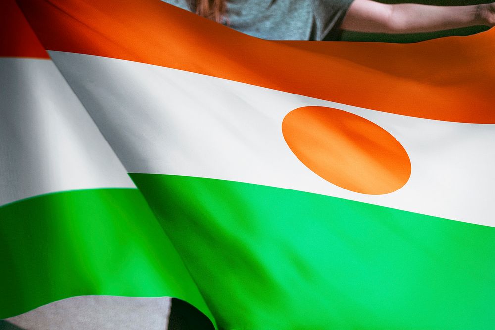 Person holding Niger flag background, national symbol