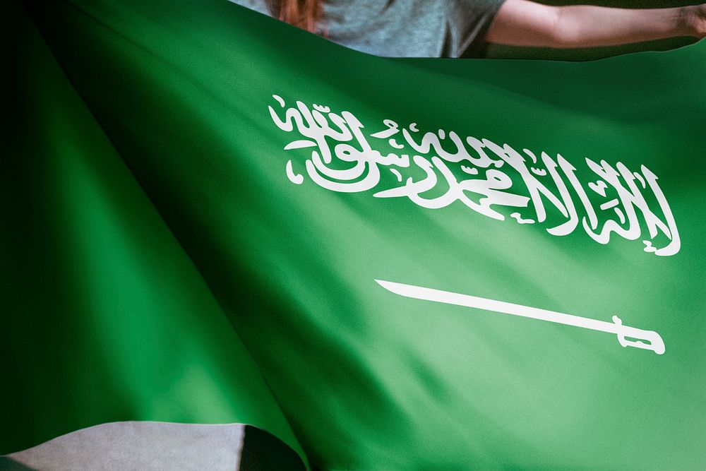 Person holding Saudi Arabian flag background, national symbol