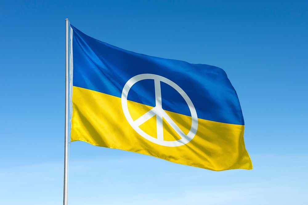 Waving Ukraine flag, peace symbol, blue sky