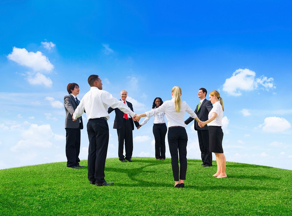 Business people holding hands on hill