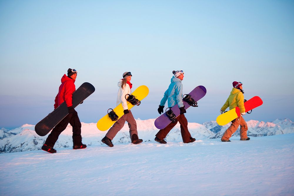 Group of snowboarders on top of the mountain.
