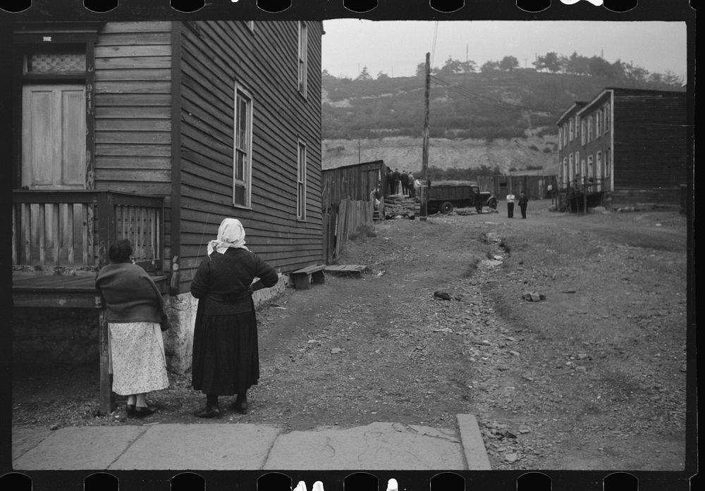 Shenandoah(?), Pennsylvania. Two women talking outside a house at the end of a street, watching some neighbors and the…