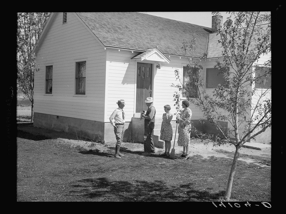 E.O. Stenquist, his wife, and one of their children talk with RR (Rural Rehabilitation) supervisor Glenn F. Cowan in front…