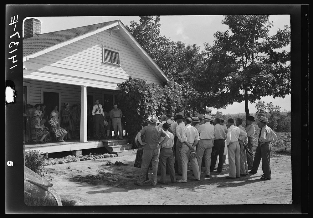 County supervisor on porch of Farm Security Administration borrower's home talking to group of local businessmen on a "Know…