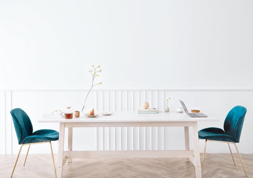 Wooden table with blue velvet chairs in a white room