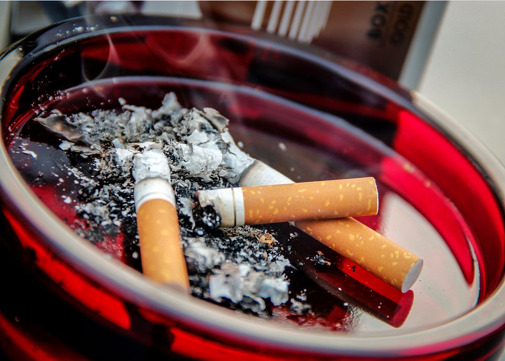 A ruby&ndash;colored glass ashtray contained three used cigarette butts along with their ashes.