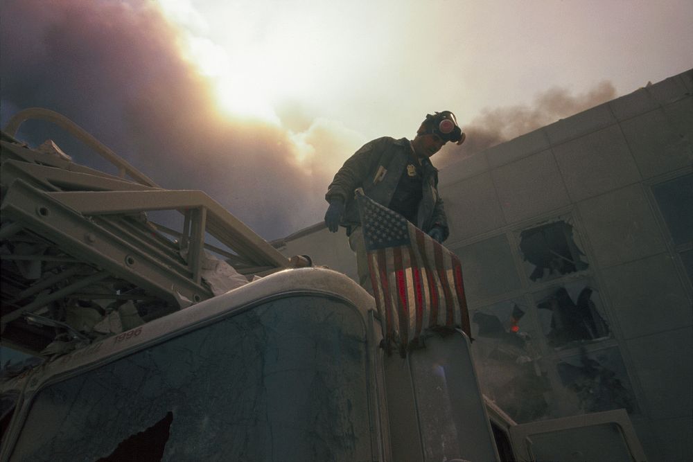 Rescue officer carrying the American flag during the aftermath of the September 11 terrorist attack on the World Trade…