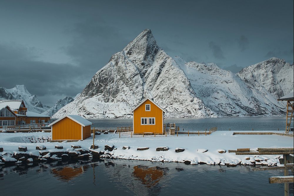 Yellow cabins by a snow lakeside on Lofoten islands, Norway