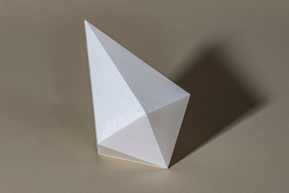 3D silver asymmetric hexagonal bipyramid paper craft on a beige background