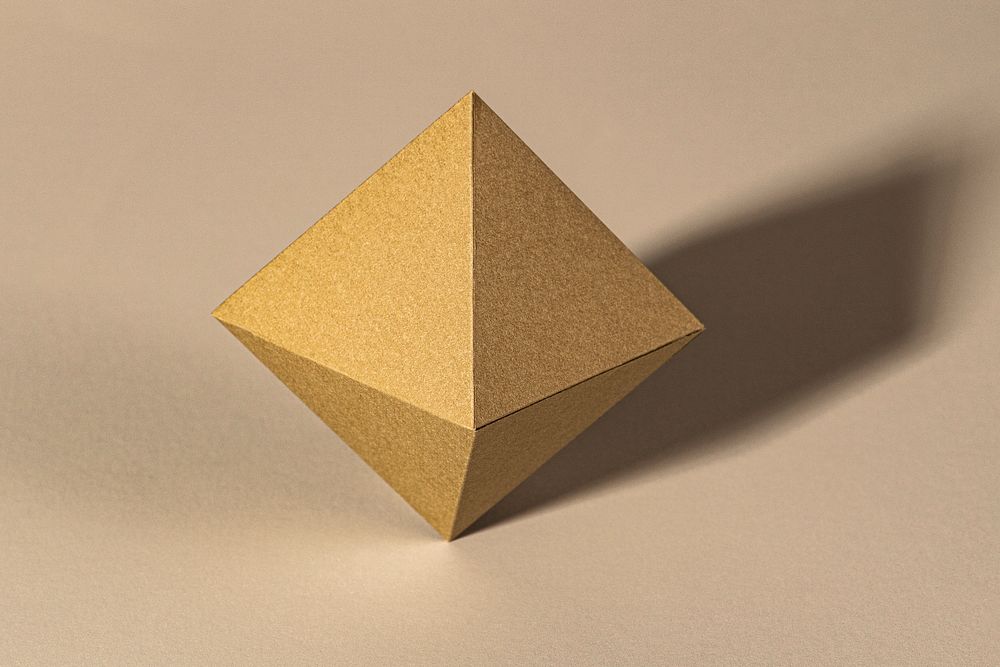 3D golden pyramid paper craft on a beige background