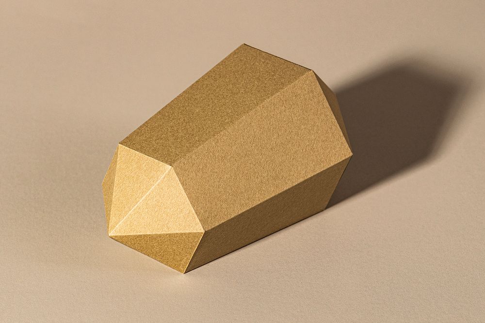 Golden hexagonal prism paper craft on a beige background