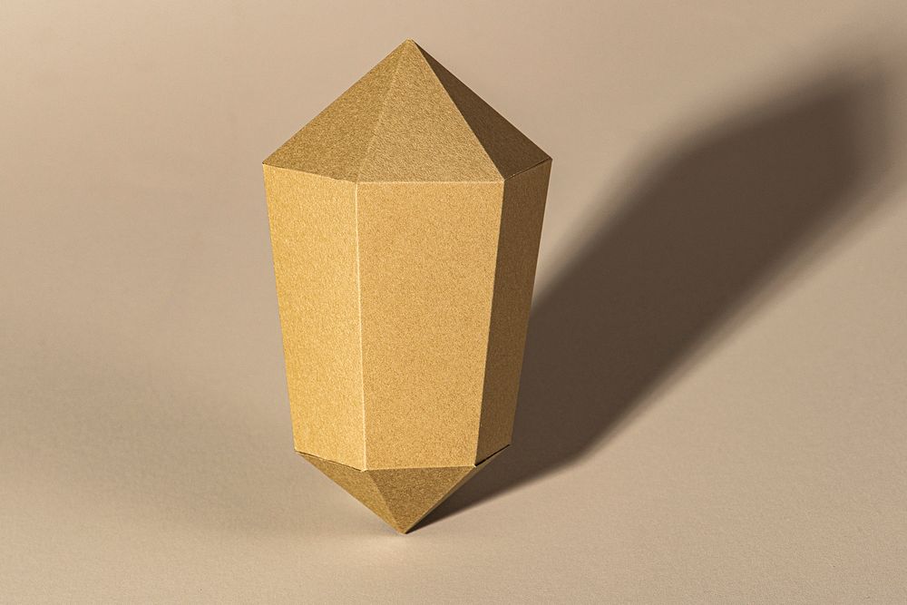 Golden hexagonal prism paper craft on a beige background