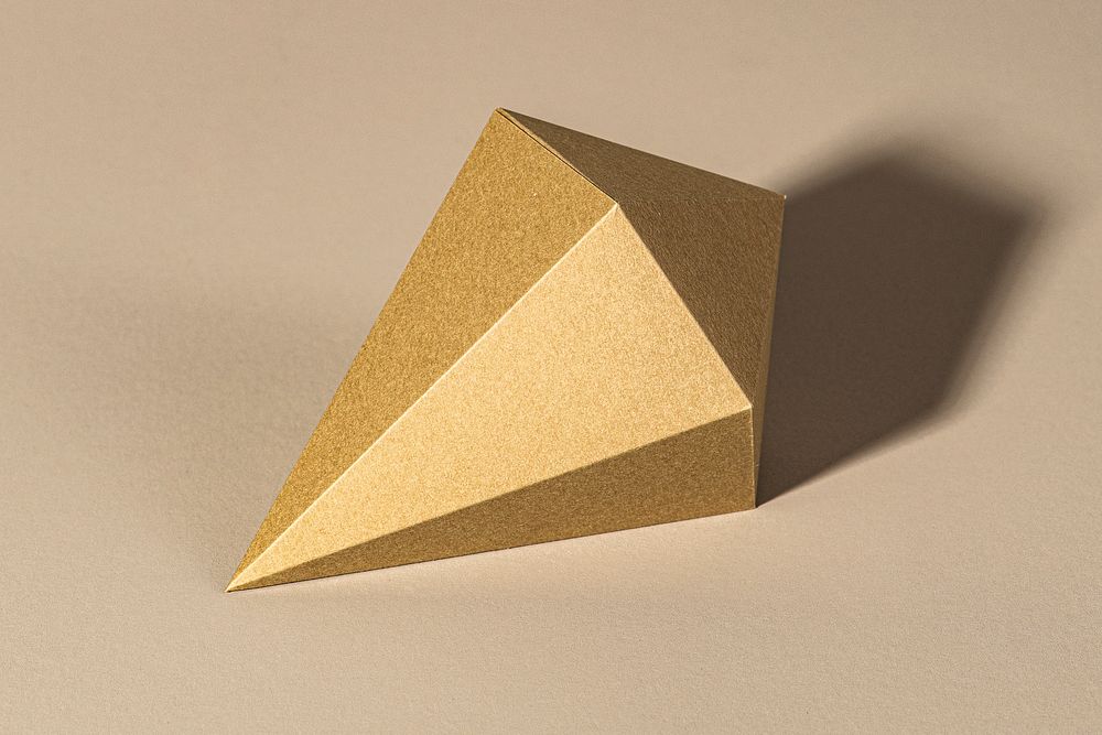 3D golden asymmetric hexagonal bipyramid paper craft on a beige background