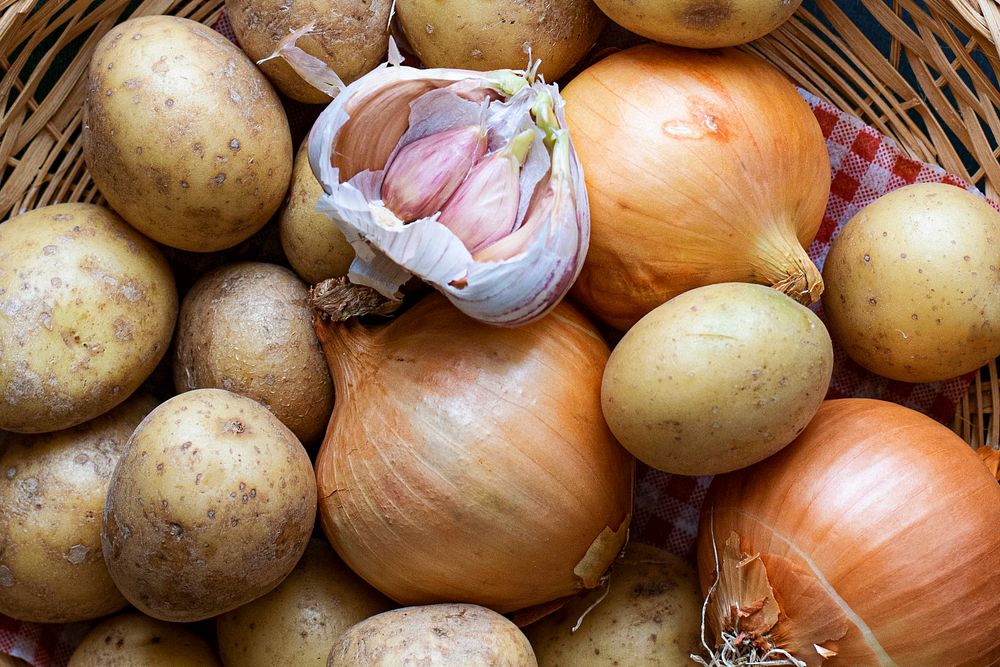 Mix raw potatoes garlic cloves and onion in brown basket