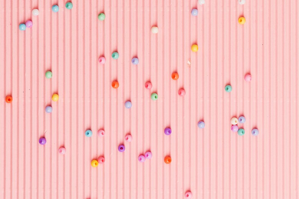 Beads on pink wavy paper wallpaper background