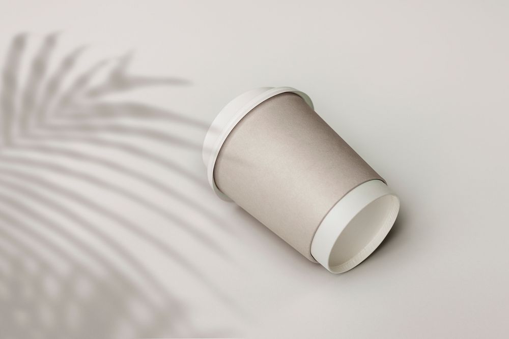 Gray paper cup with palm leaf shadow