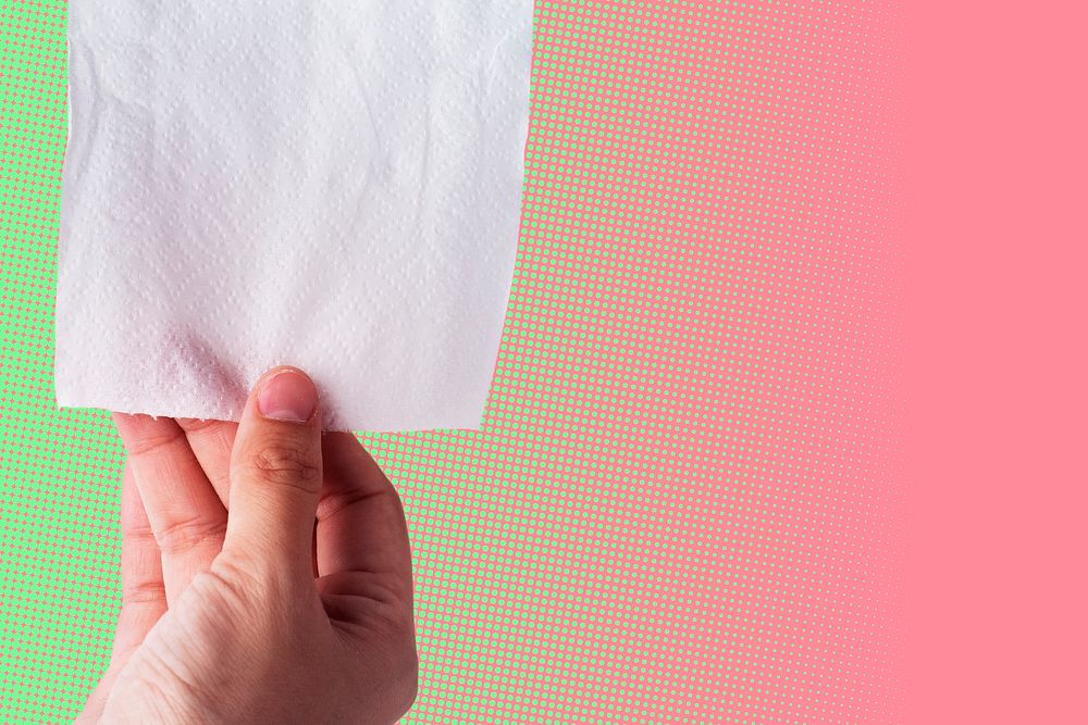 Hand getting toilet paper on pink and green background