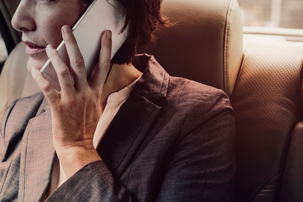Businesswoman talking on phone in back seat car