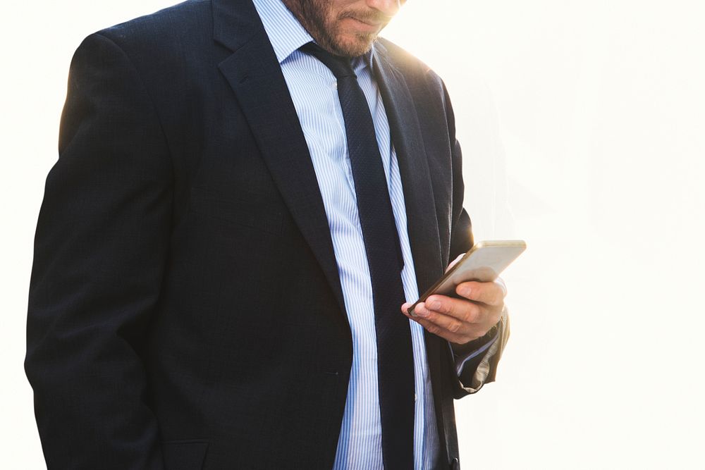 Businessman staring at smartphone off white background