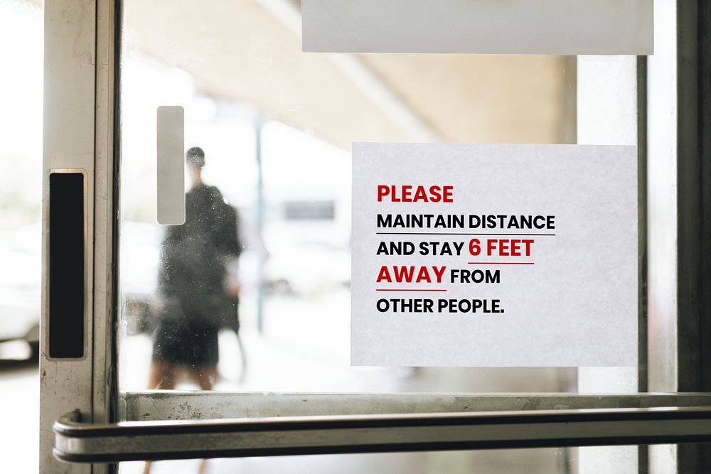 Please maintain distance and stay 6 feet away from other people paper sign on a glass door