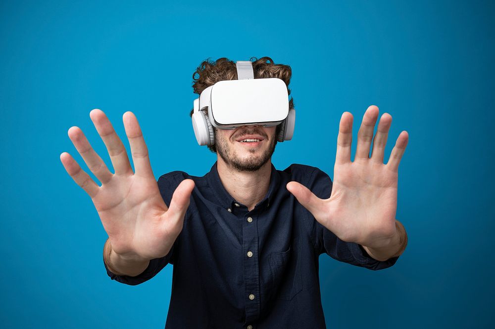 Young man using a VR headset in a blue background