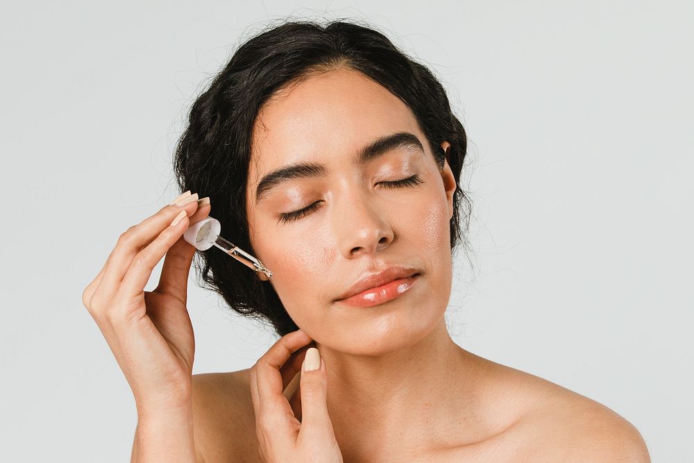 Young woman applying serum on her face 