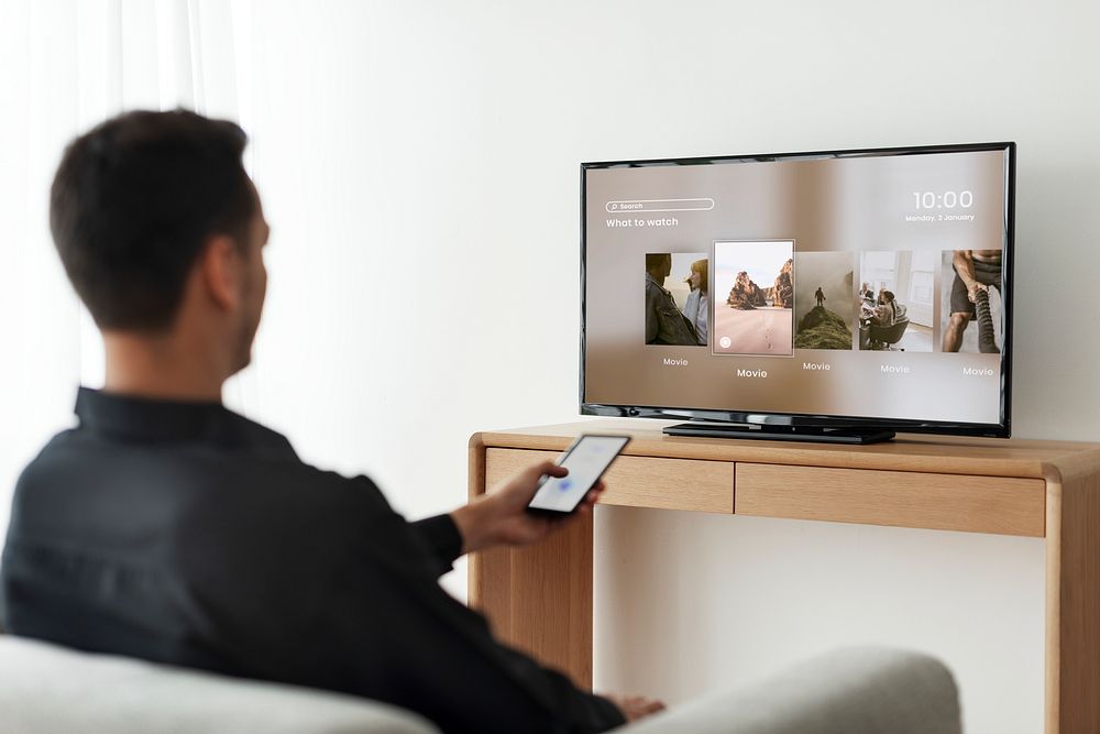 Man changing TV channel by his smartphone