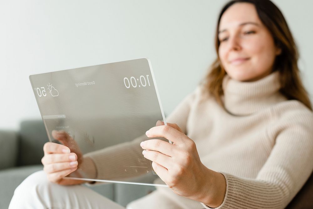 Woman using transparent tablet on a couch innovative technology