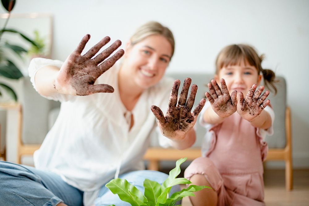 Playful mom and kid potting plant at home