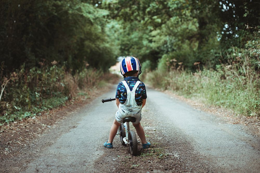 Little boy learning how to ride a bike in the forest