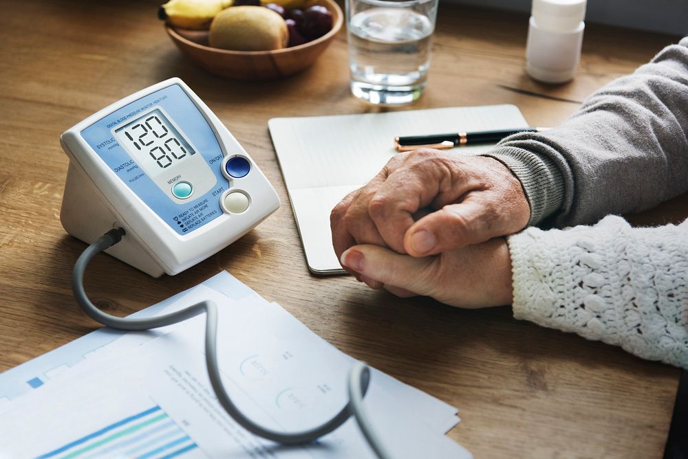 Blood pressure measure machine with senior people holding hands closeup