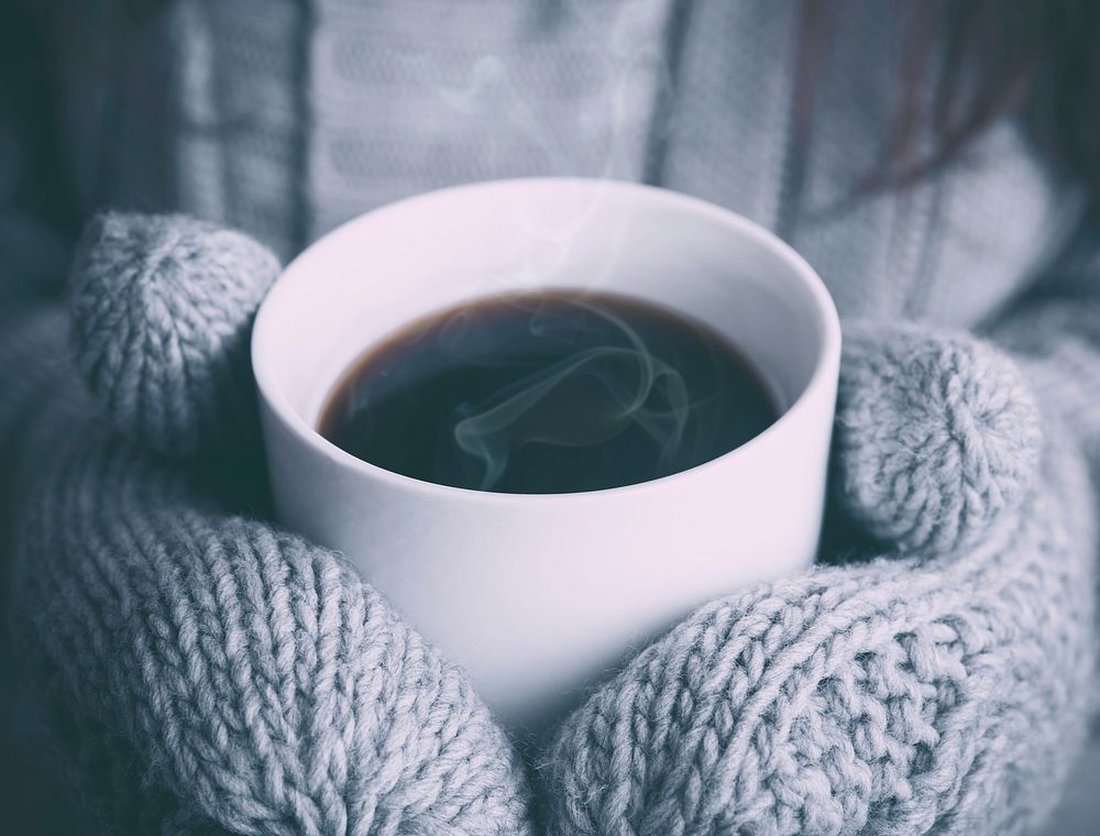 A person in mittens holding a cup of hot coffee. Original public domain image from Wikimedia Commons